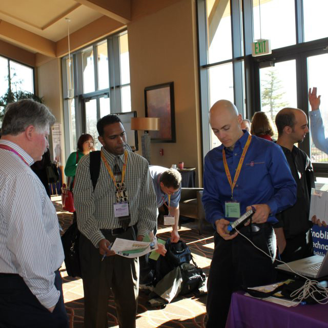 Exhibitor conversing with attendees at AHG